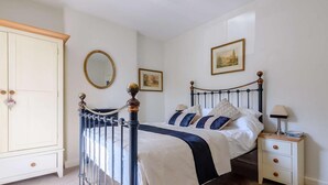 Un dormitorio con cama, mesita de noche, armario y espejo.