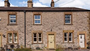 Una casa de piedra con varias ventanas, una puerta y mobiliario para exteriores.