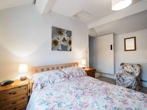 A bedroom with a bed, bedside lamps, a nightstand with a clock, a chair, and a door leading to another room. - 2 Bed in Bakewell (oc-pk932) (Ashford in the Water)