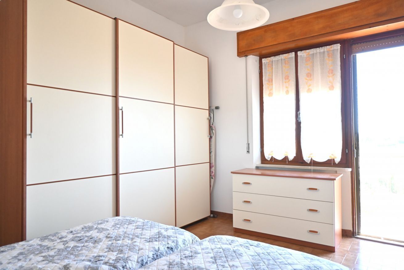 A bedroom with a bed, a wardrobe, a dresser, and a window with curtains.