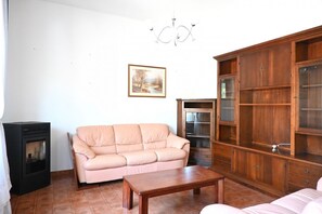 Un soggiorno con un divano beige, un mobile in legno, un caminetto e un lampadario.