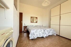 Una camera da letto con un letto, una lavatrice, uno specchio e un armadio.