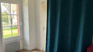 Ein Schlafzimmer mit einem Bett, einem Fenster, einer Tür und einem Vorhang.