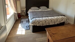 Ein Schlafzimmer mit einem Bett, Holzboden, einem Fenster mit Vorhängen, einer Lampe und einer Wand mit dem Schriftzug 'CHERIE'.