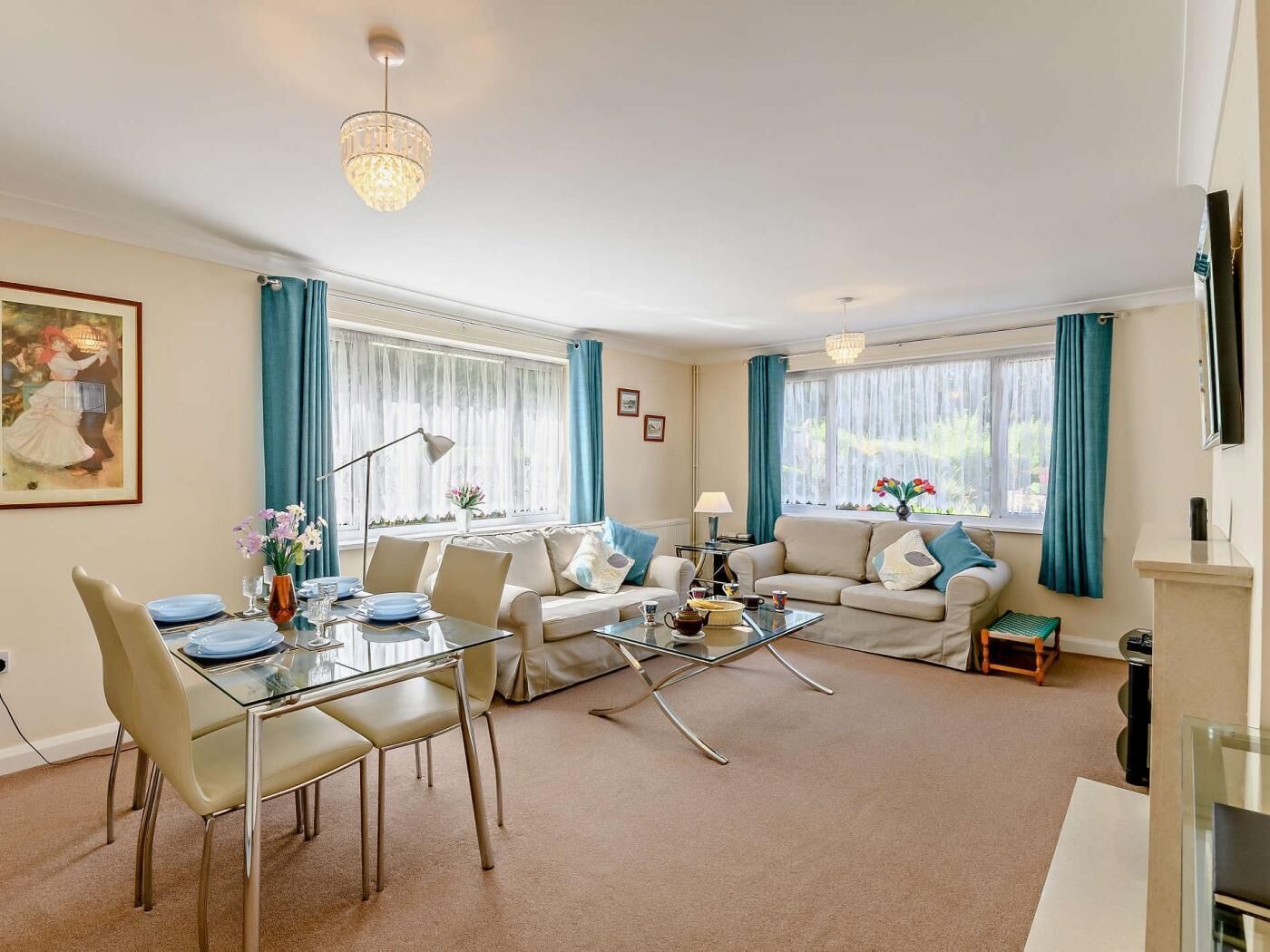 A living room with a glass dining table, two sofas, a coffee table, and a TV.