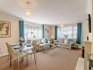 Ein Wohnzimmer mit einem Glastisch, zwei Sofas, einem Couchtisch und einem Fernseher.