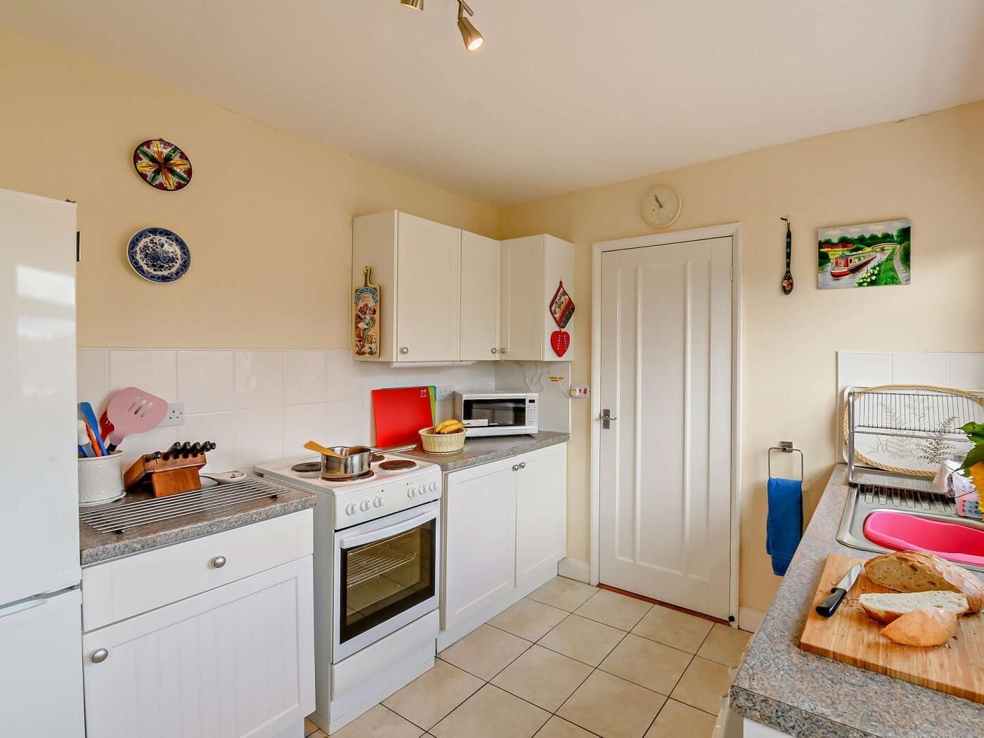A compact kitchen with white cabinets, a microwave, a stove, and a sink.