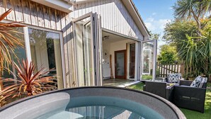 Ein modernes Haus mit einem gläsernen Whirlpool, Gartenmöbeln und einem Holzzaun.
