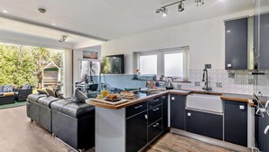 Eine moderne Küche mit Essbereich, ausgestattet mit einer integrierten Kochinsel, schwarzen Schränken und einem großen Fenster.