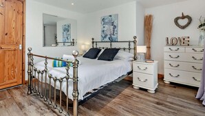 Ein Schlafzimmer mit einem Bett, einem Schminktisch, einem Spiegel und Bildern an den Wänden.
