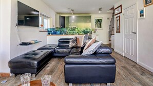 Ein modernes Wohnzimmer mit einem Ecksofa, einem Couchtisch und einer Küche im Hintergrund.