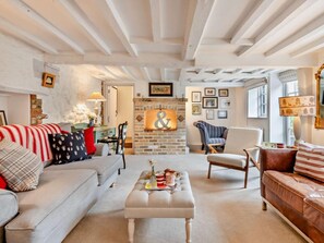 Ein gemütliches Wohnzimmer mit Kamin, Sofa, Couchtisch und einem gestreiften Sessel.