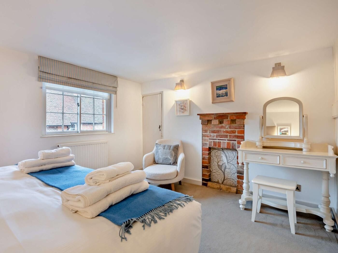 Ein Schlafzimmer mit Bett, Stuhl, Kommode, Kamin und Fenster.