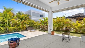 A covered outdoor area with a pool, lounge chairs, and a ceiling fan. - Modern 3BR Villa With Private Pool in Oasis del Lago by Vistacana Rentals (Punta Cana)