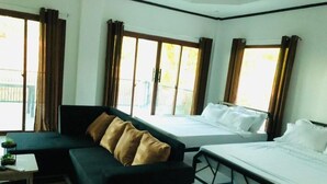 A hotel room with a sofa, a bed, and a window with curtains.