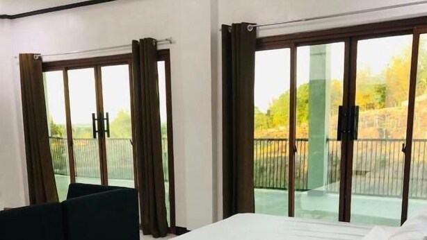A hotel room with two beds, large windows, and a view of a balcony.