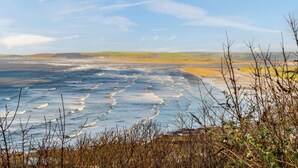 A coastal landscape with a view of the sea, distant hills, and sparse vegetation. - 3 Bed in Bideford (oc-46252) (Northam)