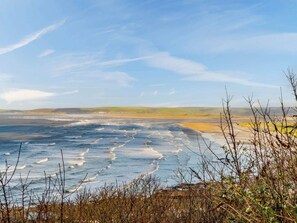 A coastal landscape with a view of the sea, distant hills, and sparse vegetation. - 3 Bed in Bideford (oc-46252) (Northam)