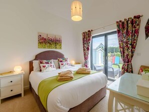 Een slaapkamer met een bed, nachtkastjes, een bureau en uitzicht.