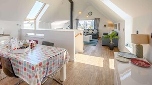 A modern loft apartment with a dining area, kitchen, and living space, featuring skylights and a loft bed. - 3 Bed in Bideford (oc-46252) (Northam)