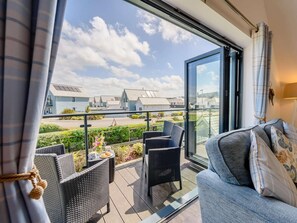 Ein Balkon mit Korbmöbeln, einer Couch und Blick auf moderne Gebäude.