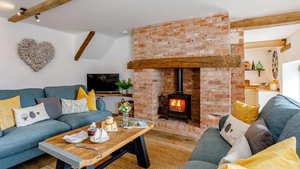 A living room with a brick fireplace, a sofa set, a coffee table, and a television. - 4 Bed in Honiton (oc-45563) (Payhembury)