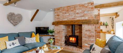 A living room with a brick fireplace, a sofa set, a coffee table, and a television.