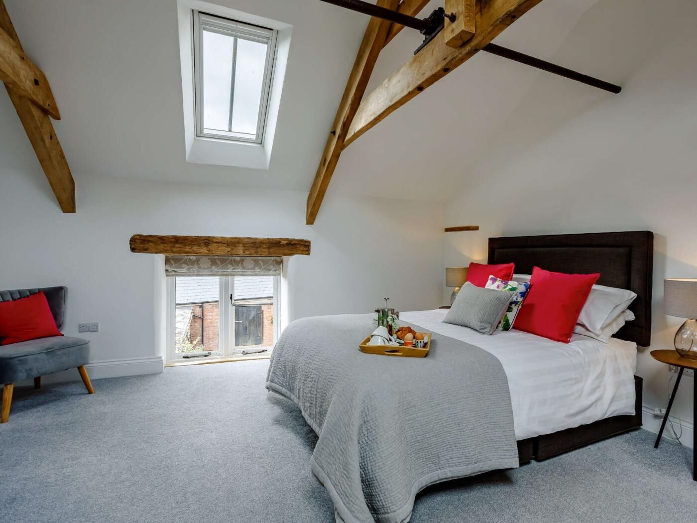 A bedroom with a large bed, a window, a sofa, and a small table.