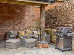 Ein gemütlicher Außenbereich mit Ecksofa, Hocker und Grill.