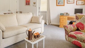 A living room with a sofa, a coffee table with a pitcher and cups, a patterned armchair, a desk with a computer, and framed pictures on the wall. - 2 Bed in Bakewell (oc-46032) (Bakewell)