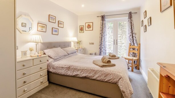 A bedroom with a bed, bedside tables, a dresser, a chair, and a window with curtains. - 2 Bed in Bakewell (oc-46032) (Bakewell)