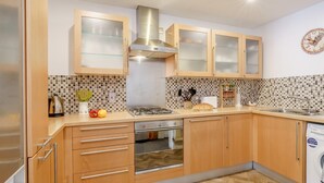 A modern kitchen with wooden cabinets, a stainless steel range hood, a built-in oven, and a dishwasher. - 2 Bed in Bakewell (oc-46032) (Bakewell)