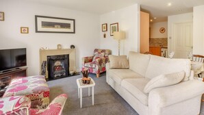 A living room with a fireplace, sofa, armchair, television, and a small table with cups. - 2 Bed in Bakewell (oc-46032) (Bakewell)