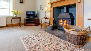 Ein gemütliches Wohnzimmer mit Kamin, Fernseher und Dekorationselementen.