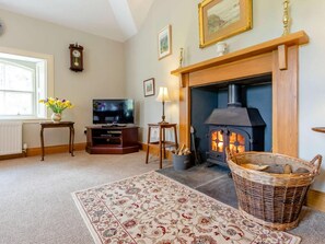 Ein gemütliches Wohnzimmer mit Kamin, Fernseher und Dekorationselementen.
