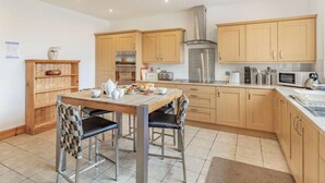 Een moderne keuken met houten kastjes, een roestvrijstalen afzuigkap en een eethoek met een tafel en stoelen.