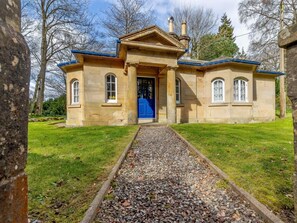 A stone building with a blue door, a gravel path leading to it, and a grassy lawn. - 1 Bed in Cupar (oc-45667) (Ladybank)