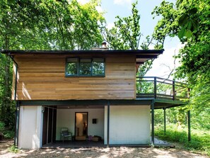 Eine zweistöckige Holzhütte mit einem Balkon, einer Veranda und einem kleinen Eingangsbereich.