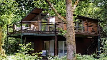 A cabin with a balcony, surrounded by trees.