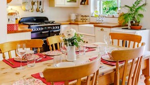 A dining area with a table set for four, surrounded by wooden chairs. A stove and cabinets are visible in the background. - 2 Bed in Sway (oc-nfl43) (Sway)