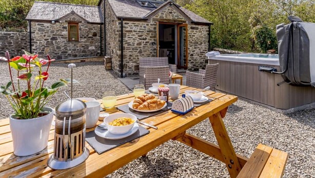 A stone house with a patio, outdoor seating, and a hot tub. - 2 Bed in Aberaeron (oc-45333) (Aberaeron)