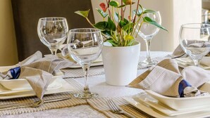 A dining table set with plates, cutlery, and wine glasses, with a potted plant in the center. - 2 Bed in Aberaeron (oc-45333) (Aberaeron)