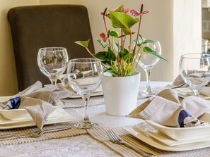 A dining table set with plates, cutlery, and wine glasses, with a potted plant in the center. - 2 Bed in Aberaeron (oc-45333) (Aberaeron)