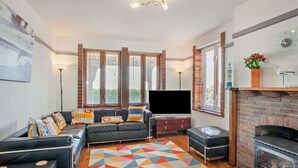 A living room with a black sofa, a flat-screen TV, a fireplace, and a colorful geometric rug. - 4 Bed in Pevensey Bay (oc-bt069) (Pevensey Bay)