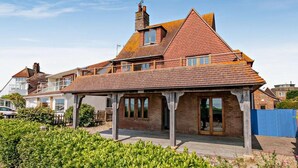 A large, two-story house with a prominent gabled roof, a covered porch, and a brick exterior. - 4 Bed in Pevensey Bay (oc-bt069) (Pevensey Bay)