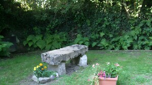 A stone bench in a garden with grass and potted plants. - The "Grand Reu" Cottage - Gite Camille (Corancy)