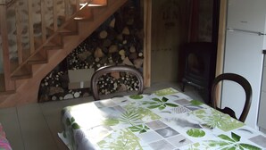 A room with a wooden staircase, a bed with a leaf-patterned bedspread, a chair, and a refrigerator. - The "Grand Reu" Cottage - Gite Camille (Corancy)