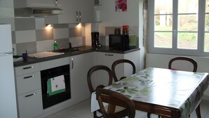 A compact kitchen with a dining table, chairs, and a window with a view. - The "Grand Reu" Cottage - Gite Camille (Corancy)