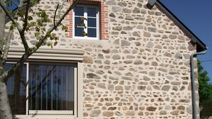 A stone building with a large window, a small balcony, and a blue chair outside. - The "Grand Reu" Cottage - Gite Camille (Corancy)