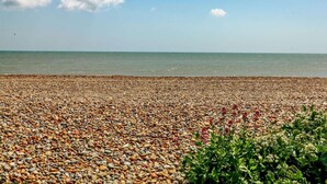Ein Kiesstrand bei klarem Himmel und ruhiger See.